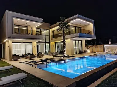 a large swimming pool in front of a house at night at Villa Moderne au sein du Golf Amelkis in Marrakech
