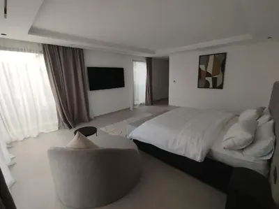 a bedroom with a bed and a chair and a tv at Villa Moderne au sein du Golf Amelkis in Marrakech