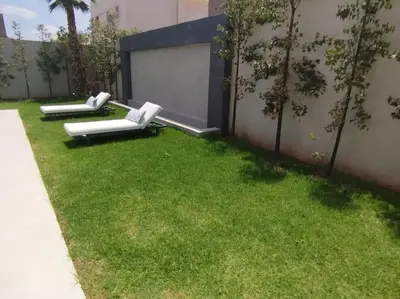 two white lounge chairs sitting in a yard at Villa Moderne au sein du Golf Amelkis in Marrakech