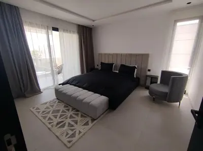 a bedroom with a large bed and a chair at Villa Moderne au sein du Golf Amelkis in Marrakech