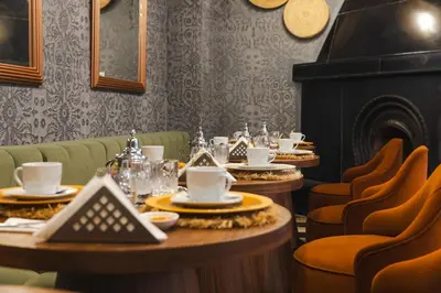 a dining room with tables and chairs and a fireplace at Riad JW Yacout, vivez l'expérience Medina in Marrakech