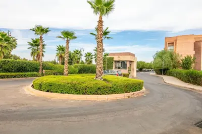 a roundabout with palm trees in front of a building at Appartement luxe Prestige Opale Golf in Marrakech