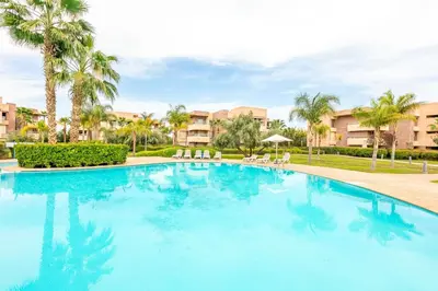 a large swimming pool with palm trees and buildings at Appartement luxe Prestige Opale Golf in Marrakech