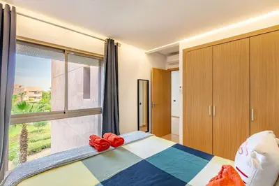 a bedroom with a bed and a large window at Appartement luxe Prestige Opale Golf in Marrakech
