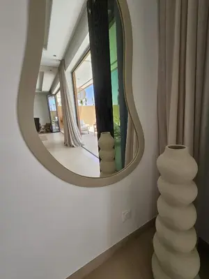 a round mirror in a room with a vase at Domaine de Kali, villa 2 au calme, piscine privée in Marrakech