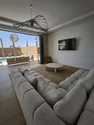 a living room with a large couch and a tv at Domaine de Kali, villa 2 au calme, piscine privée in Marrakech