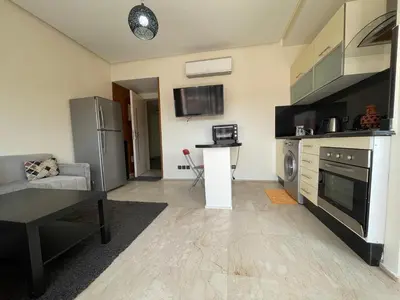 a living room with a couch and a kitchen at Cosy appartement au Centre de Marrakech in Marrakech