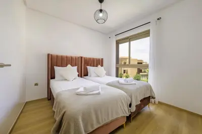 a bedroom with two beds with white sheets and a window at Vue Montagnes, Golf et Piscine, Luxe à Marrakech in Marrakech