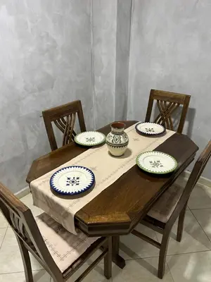 a wooden table with four chairs and plates on it at Cosy & Calm appartement in Marrakech