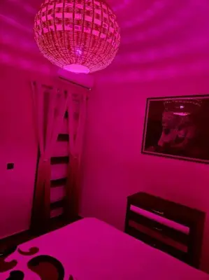 a pink room with a chandelier and a bed at Le cœur de L'orient Marrakech in Marrakech