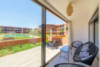 a balcony with a view of a pool and chairs at Appartement NOVA Noria in Marrakech