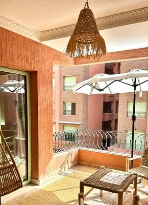 a balcony with an umbrella and a table and chairs at Beautiful Hivernage Apartment with Pool & Balcony, Near Attractions in Marrakech