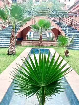 a palm tree in front of a building with stairs at Beautiful Hivernage Apartment with Pool & Balcony, Near Attractions in Marrakech