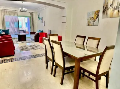 a dining room and living room with a table and chairs at Beautiful Hivernage Apartment with Pool & Balcony, Near Attractions in Marrakech