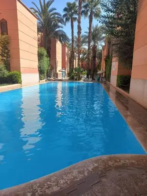 a large blue swimming pool in a building with palm trees at Riad Selma résidence face Médina avec Piscines in Marrakech