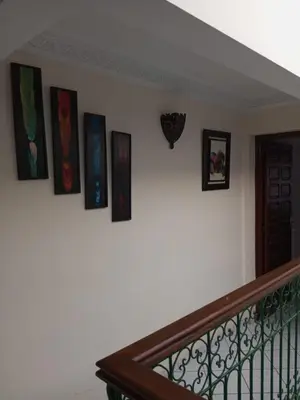 a group of paintings on a wall next to a staircase at Riad Selma résidence face Médina avec Piscines in Marrakech