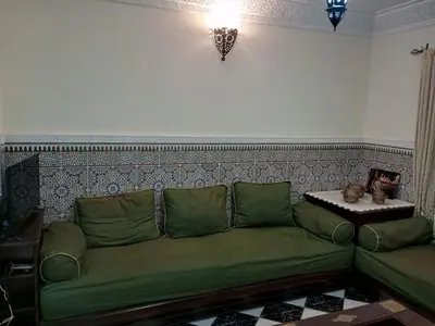 a green couch in a living room with a table at Riad Selma résidence face Médina avec Piscines in Marrakech