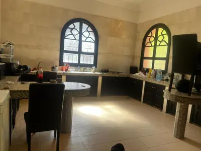a large kitchen with a table and two windows at Splendide villa de charme à Marrakech in Marrakech