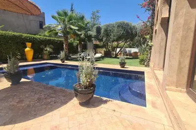 a swimming pool with potted plants next to a house at Villa LES LAURIERS, 4 suites, piscine privée, petit déjeuner compris in Marrakech