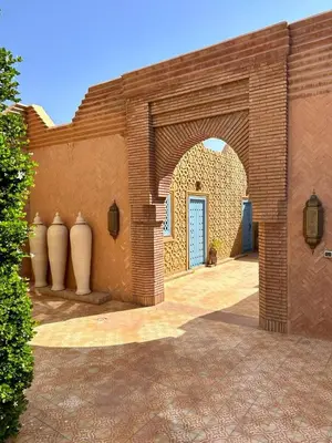 a brick building with an archway and a blue door at Villa Shambhala in Marrakech
