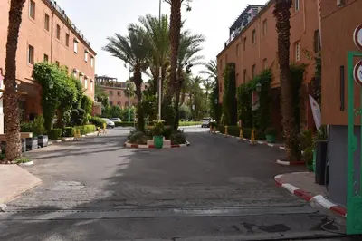 an empty street with palm trees and buildings at Riad butterfly Marrakech in Marrakech