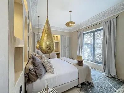 a bedroom with a large bed and a chandelier at Riad Azrak in Marrakech