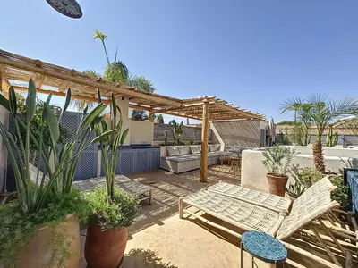 a patio with a couch and a pergola with plants at Riad Azrak in Marrakech