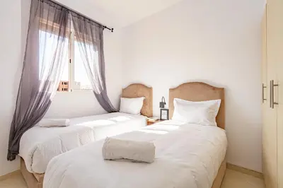 two beds in a room with a window at Appartement familial à Marrakech in Marrakech