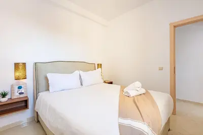 a bedroom with a white bed and a mirror at Appartement familial à Marrakech in Marrakech