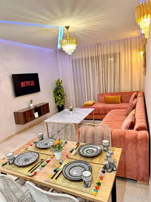 a living room with a table and a couch at PEARL GARDEN Luxueux Studio Chic Piscine Terrasse Netflix IPTV Parking in Marrakech
