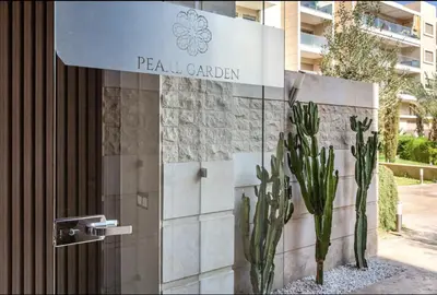 a sign for a hotel with cactus in front of a building at PEARL GARDEN Luxueux Studio Chic Piscine Terrasse Netflix IPTV Parking in Marrakech