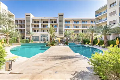 a swimming pool in front of a large apartment building at PEARL GARDEN Luxueux Studio Chic Piscine Terrasse Netflix IPTV Parking in Marrakech