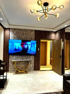 a living room with a large tv on a stone wall at Appartement luxueux, cosy & confortable in Marrakech