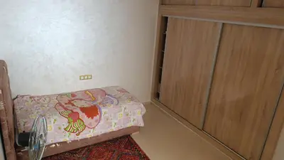 a small bedroom with a bed and a wooden cabinet at Chez bousfyha 2 in Marrakech