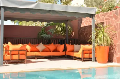 an outdoor seating area with orange pillows next to a pool at Atlas Royale Marrakech in Marrakech
