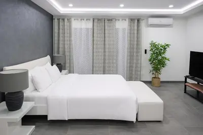 a white bedroom with a white bed and a tv at Atlas Royale Marrakech in Marrakech