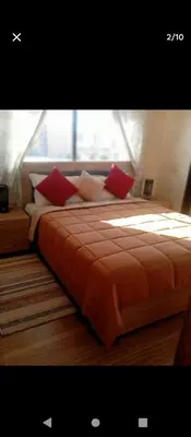 a bed with red pillows in a room with a window at Magnifique appartement in Marrakech