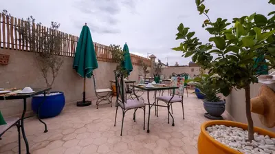 a patio with tables and chairs and green umbrellas at Riad dei colori in Marrakech