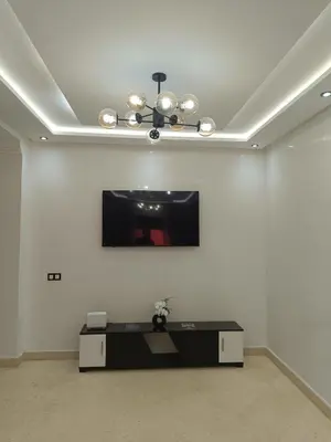a living room with a tv on a white wall at Riad Arfoud appartement haut standing 3 chambres avec piscine à gueliz nord in Marrakech