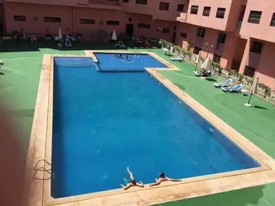 a large swimming pool with two people laying in it at Riad Arfoud appartement haut standing 3 chambres avec piscine à gueliz nord in Marrakech