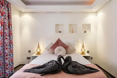 two swans wrapped in towels sitting on a bed at Magnifique appartement Gueliz in Marrakech