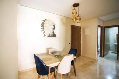 a dining room with a wooden table and blue chairs at Appartement de lux in Marrakech