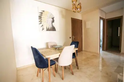 a dining room with a wooden table and blue chairs at Appartement de lux in Marrakech