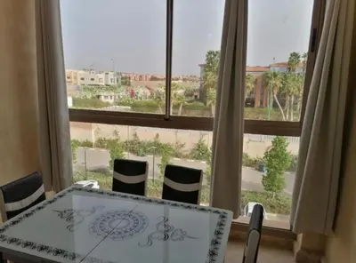 a table and chairs in front of a large window at Charming Apartment in the Heart of Marrakech - Modern Amenities and Prime Location in Marrakech