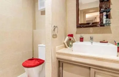 a bathroom with a sink and a toilet with a red seat at Charming Apartment in the Heart of Marrakech - Modern Amenities and Prime Location in Marrakech