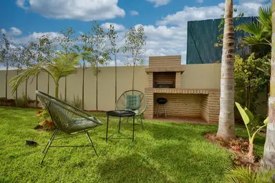 a garden with two chairs and a hammock in the grass at Somptueuse Family Villa Cherifa avec piscine chauffée in Marrakech