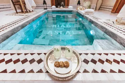 a table with a plate of food next to a swimming pool at Riad Aslal in Marrakech