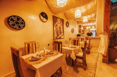 a restaurant with tables and chairs with a man in the background at Riad Aslal in Marrakech