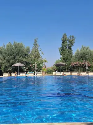 a swimming pool with blue water and umbrellas at les jardins d'atlas waky palm golf in Marrakech