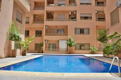 a swimming pool in front of an apartment building at Superbe appart cosy avec piscine in Marrakech